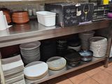 many plates and bowls sitting on a shelf in the kitchen
