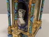 a gold and blue clock with a picture of a woman on it