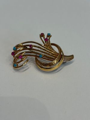 une broche en or ornée de pierres roses et bleues