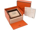 an orange box with a watch inside of it on a white surface