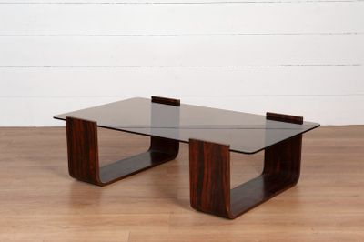 une photo d'une table basse avec un plateau en verre posée sur un parquet