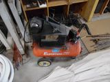 un petit compresseur d'air posé dans un garage avec d'autres outils