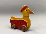 a wooden toy duck that is sitting on a cart