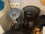 a black coffee maker sitting on a counter next to a frying pan