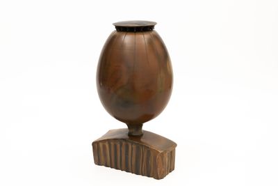 a wooden vase with a black lid on a stand