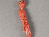 une figurine orange représentant une femme avec un oiseau sur la tête