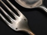a silver fork and a silver spoon on a black table