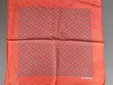 an orange silk pocket square with a pattern on it