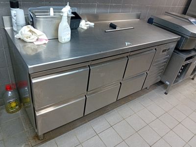 un plan de travail en acier inoxydable dans une cuisine professionnelle, sur lequel sont posés de nombreux objets