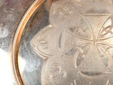 a silver plate with a design on it sitting on a table