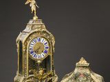 an antique clock with a statue on top of it next to a small clock