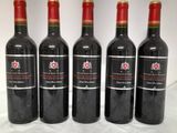 four bottles of red wine are lined up on a table