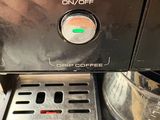 a close up of a coffee maker with a person ' s hand on it