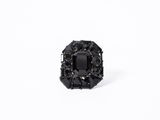 a close up of a black diamond ring on a white surface