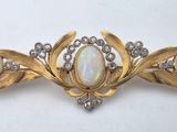 an oplite and diamond broochle is displayed on a white surface