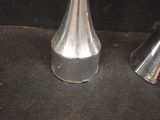 two silver vases sitting next to each other on a black surface