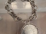 silver bracelet with a coin on a chain on a table