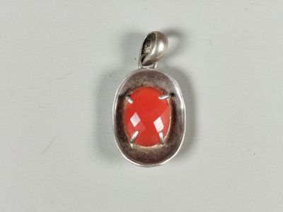 an image of a red stone in a silver pendant on a white surface