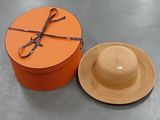une boîte orange avec un chapeau et une paire de ciseaux