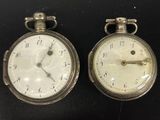 deux montres de poche en argent posées côte à côte sur une surface noire