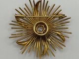 a close up of a gold brooch with a diamond in the center