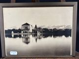 an old photo of a church on a lake with mountains in the background