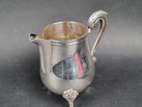 a small silver pitcher with a handle on a table