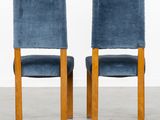 a pair of blue velvet chairs with wooden legs