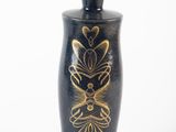 a black vase with gold designs on it on a white surface