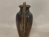 a brown and blue vase sitting on a white surface