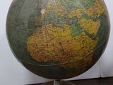 un globe vert et jaune posé sur un socle en bois