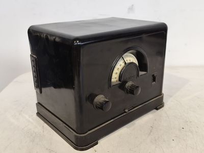 une vieille radio noire posée sur une table blanche