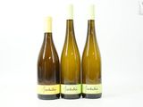 trois bouteilles de vin posées les unes à côté des autres sur une surface blanche