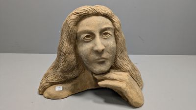 sculpture représentant le visage d'une femme aux longs cheveux, posée sur une table