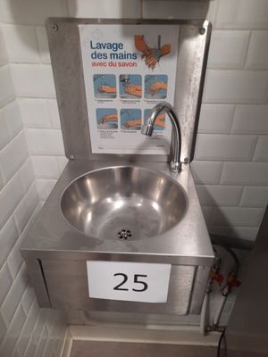 a stainless steel sink with a sign on it