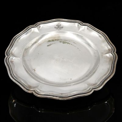 an antique silver plate on a black surface with a black background