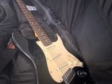 guitar in a black case sitting on top of a black couch