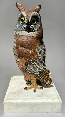 statue of an owl sitting on a white pedestal with a gray background