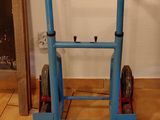 a blue hand truck that is sitting on a tiled floor