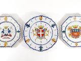 three plates with a coat of arms on them on a white surface
