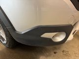 the front bumper of a silver car with a hole in it