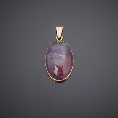 a gold pendant with a purple stone in the center