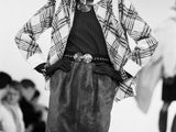 a black and white photo of a woman walking down a runway