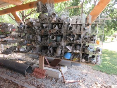 une pile de casseroles et de poêles posée sur un support dans une cour