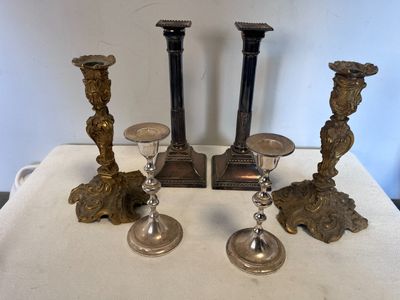 trois bougeoirs en argent posés les uns à côté des autres sur une table