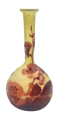 un vase jaune et marron orné de fleurs, posé sur une surface blanche