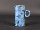 a small blue vase with a handle on a table