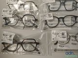 several pairs of glasses are in plastic bags on a table