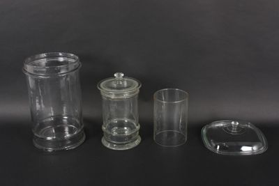 three clear glass containers with lids and lids on a black surface