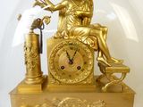 une horloge dorée représentant une femme assise sur un banc